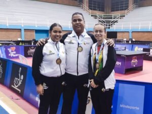 estudiante María Camila Cervera, con una compañera de equipo y su entrenador