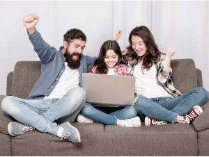 Un padre y una madre, juntamente con su hija en el computador celebrando.