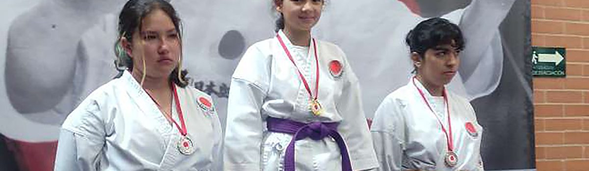 la estudiante Oriana Moreno en el podio de primer lugar, junto a otras concursantes en segundo y tercer lugar