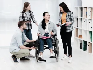  Un grupo de jovenes alrededor de una muchacha en silla de ruedas