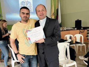 El rector P. Eduin y el profesor William Ruiz entregando un reconocimiento