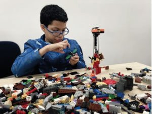 estudiante de primaria incluyente realizando una construcción con legos