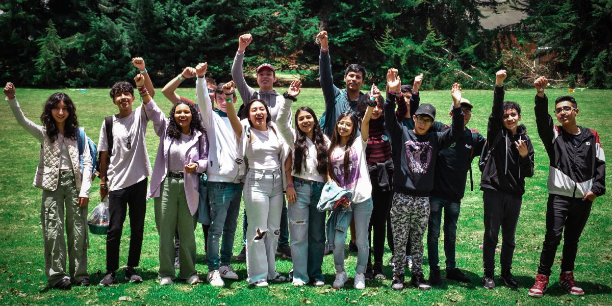 Alumnos del Cibercolegio UCN levantando su mano empuñada y soriendo a la cámara.
