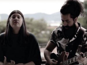 Una jóven y un jóven cantando y tocando la guitarra
