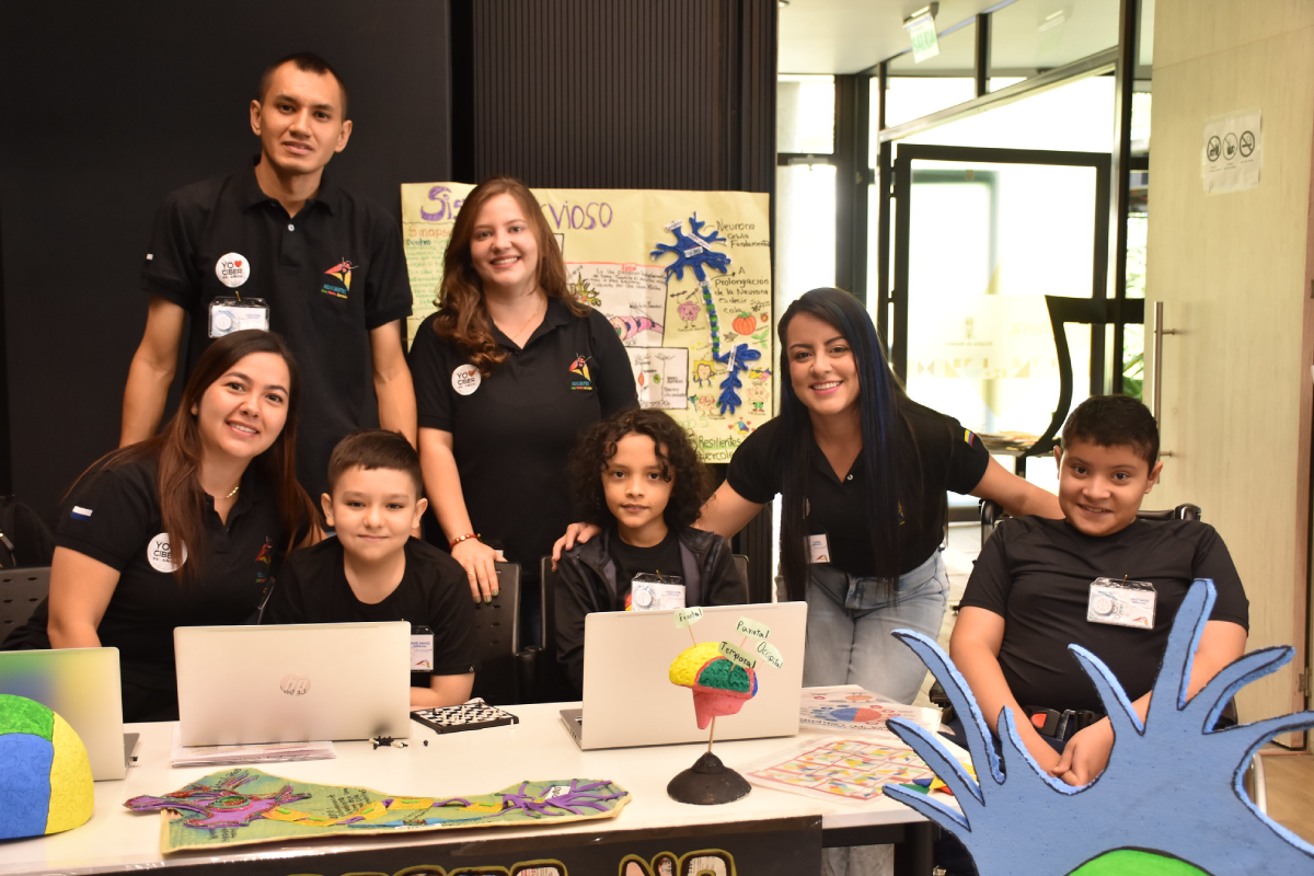 Fotografía donde se observa un microscopio y un libro sobre una mesa en una de las jornadas de la feria Cibersorprende del Cibercolegio UCN.