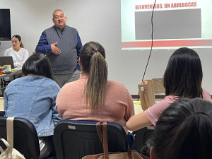 Se observa al padre rector en exposición con diapostivas. 