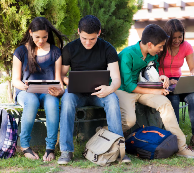 Grupo de jóvenes universitarios sentados el uno al lado del otro y con sus computadores abiertos.