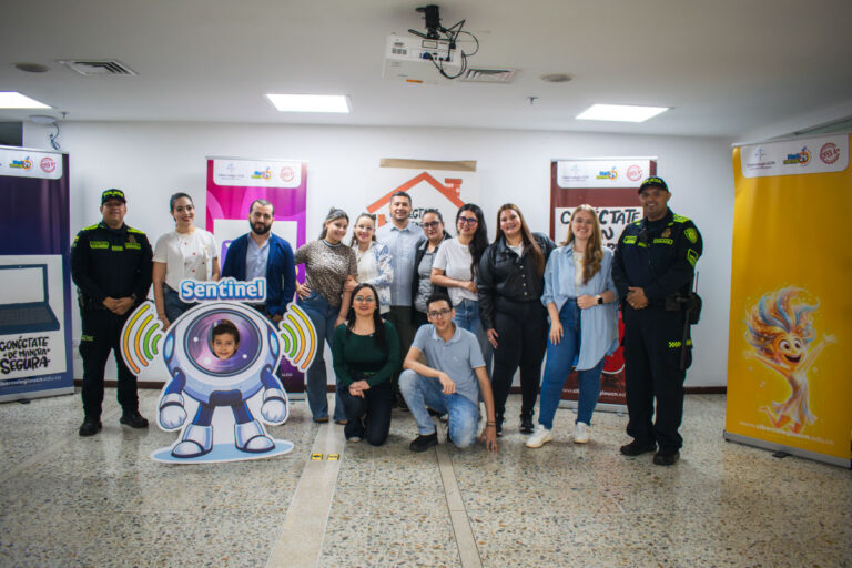Grupo de docentes, psicólogas, estudiantes e invitados especiales reunidos en el set de la jornada “Conéctate con la Vida” del Cibercolegio UCN, una campaña de promoción y prevención del consumo de sustancias psicoactivas (SPA) y la hiperconectividad. Al fondo se observan pendones institucionales y, en primer plano, una figura ilustrada del personaje Sentinel.