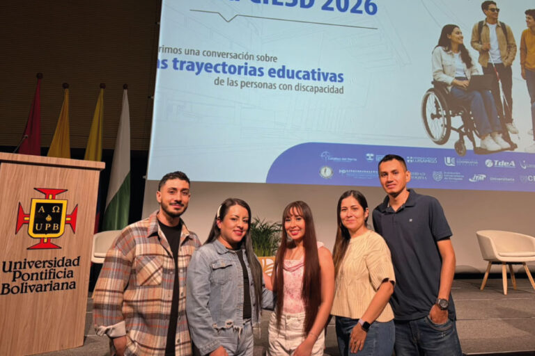 Equipo de la UCN y el Cibercolegio UCN posa en el auditorio de la Universidad Pontificia Bolivariana durante el VIII Encuentro Nacional Red CIESD 2026. En el fondo se observa una pantalla con el nombre del evento y el mensaje sobre las trayectorias educativas de las personas con discapacidad. A la izquierda se encuentra el atril institucional de la UPB y varias banderas. La imagen refleja la participación de la institución en un espacio académico dedicado a la educación inclusiva y la atención a estudiantes con discapacidad.
